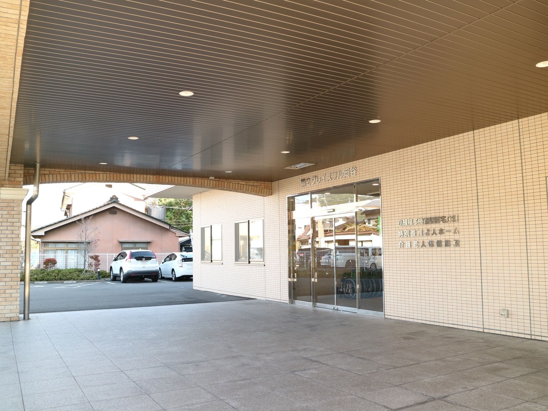 屋根付きの大きな玄関で入口は自動ドアが採用されている。敷地内にアスファルトで舗装された、駐車場が完備されている。