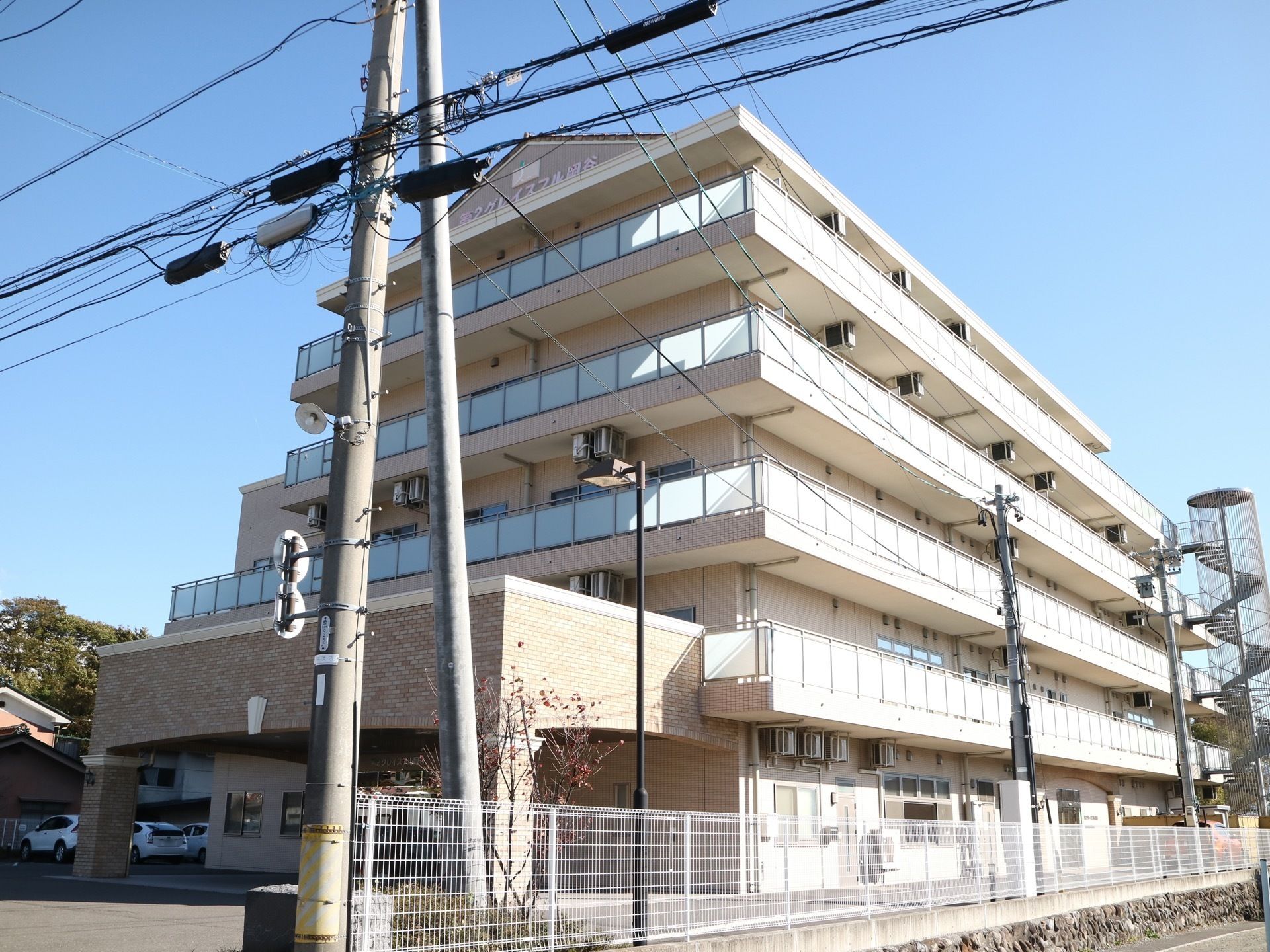 らせん状の非常階段が設置されているグループホームである。２階以上にはベランダスペースが設けられている。