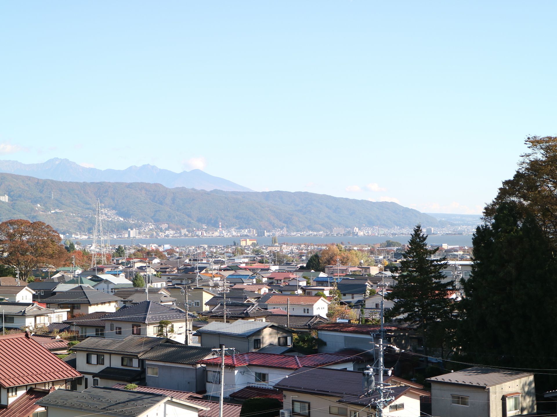 手前は住宅街、画面中央に湖、その向こうには連なる山々が眺められる高台