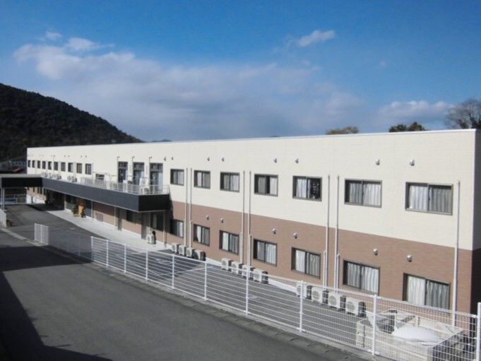 ベージュと白の２階建ての建物は横に長く、日当たりのいい場所に建っていて、周りには何もない。