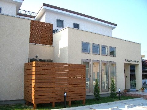 建物の前に緑のスペースがある、白い外壁を持つ施設外観