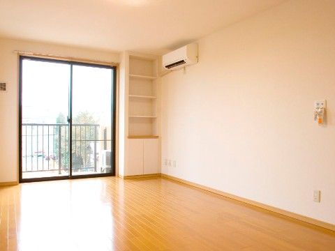奥に窓がありエアコンが設置されているが、家具が置かれていない状態の居室