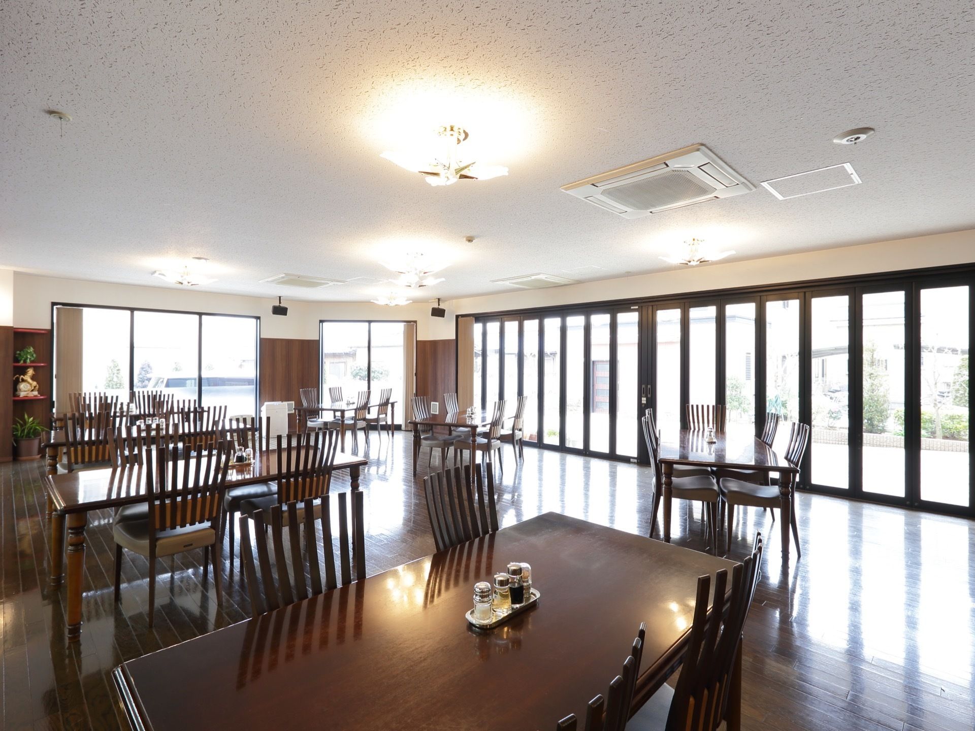 食堂の１方の壁は全面ガラス張りで明るく、開放感がある。天井にはスピーカーが設置されており、音楽が流れている。
