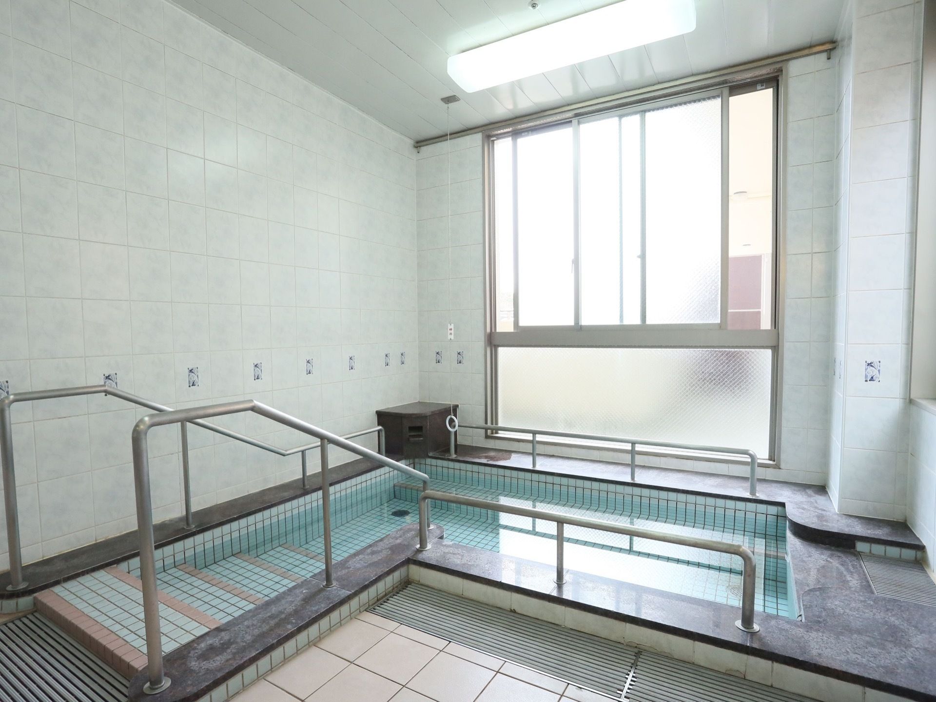 手すりや浴槽に続く階段が設置された浴室