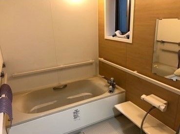 一人用の浴槽が設置された家庭的な雰囲気の浴室。手すりが壁に設置されている。