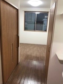 居室のドア側から見た様子。収納スペースや洗面所が右側、トイレが左側につき、広いスペースが奥に広がっている。