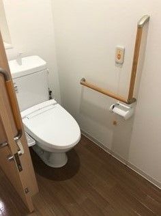 居室のトイレはシンプルなデザイン。壁にはエル字型の手すりと呼び出しボタンが付いている。