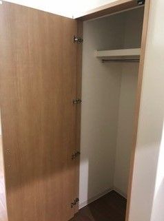 居室の収納スペース。扉を開けるとハンガーをかけるポールや小物を収納する棚もついている。