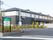 駐車場が付いたベージュの建物。玄関には屋根が付き、住宅と併設介護事業所の看板もある。