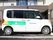 施設建物前の駐車スペースに白い施設専用車が停車している。ドアには事業所名と施設名称がロゴマークと共に明記されている。