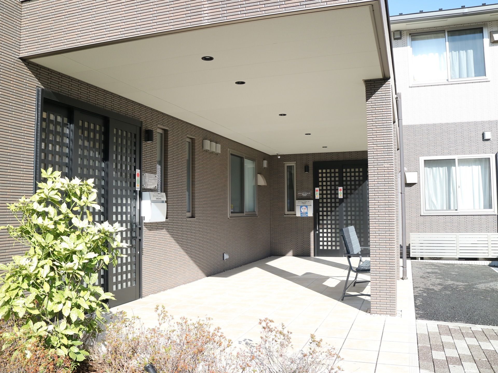 日当たりの良い施設入口である。施設内への扉が2箇所に設置されている。屋根を設けた玄関ポーチが備え付けられている。