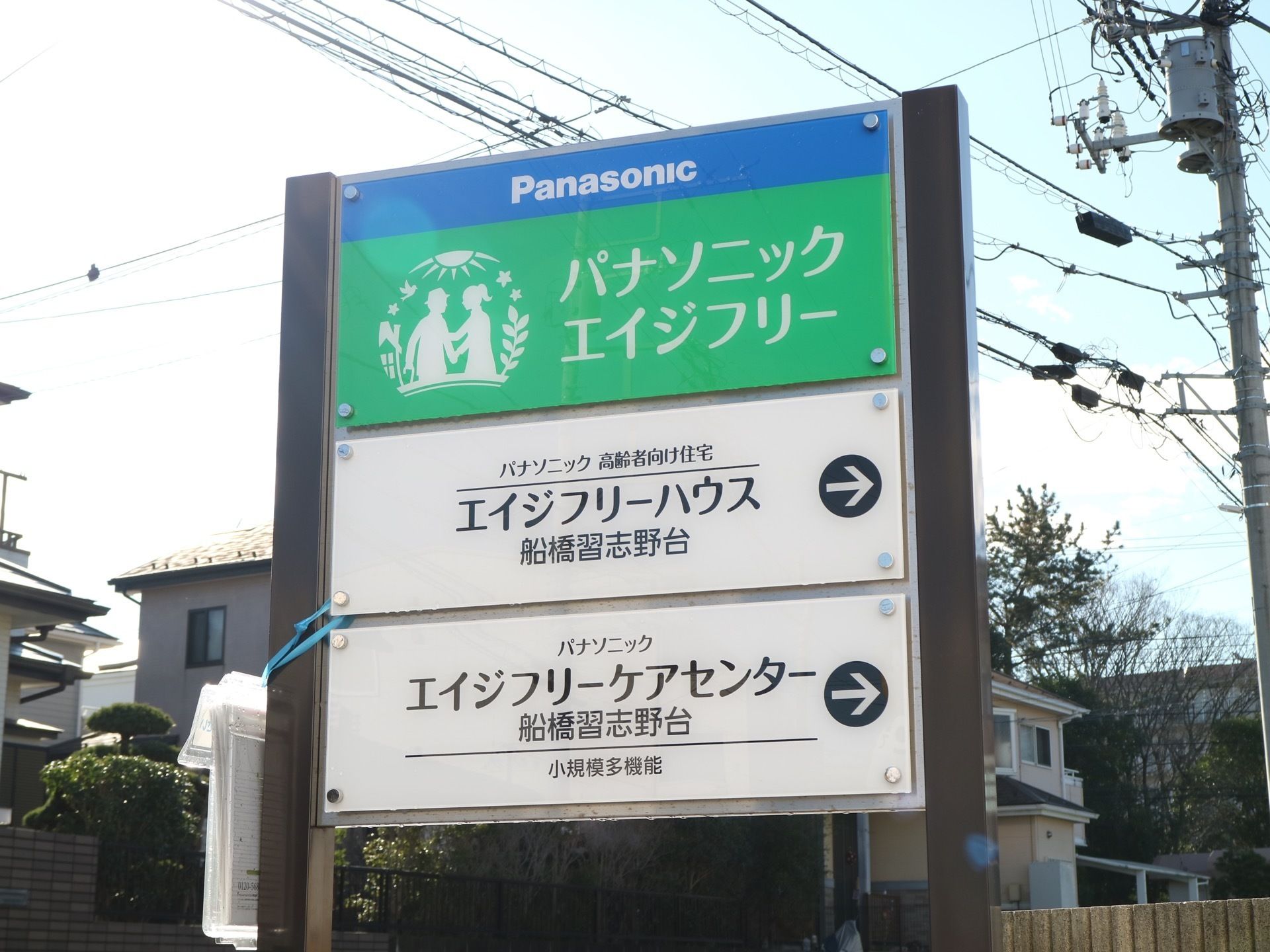 3枚の施設プレートが、ビス止めされ設置されている。企画事業所名と施設名称が種別とともに明記され、立てかけられている。