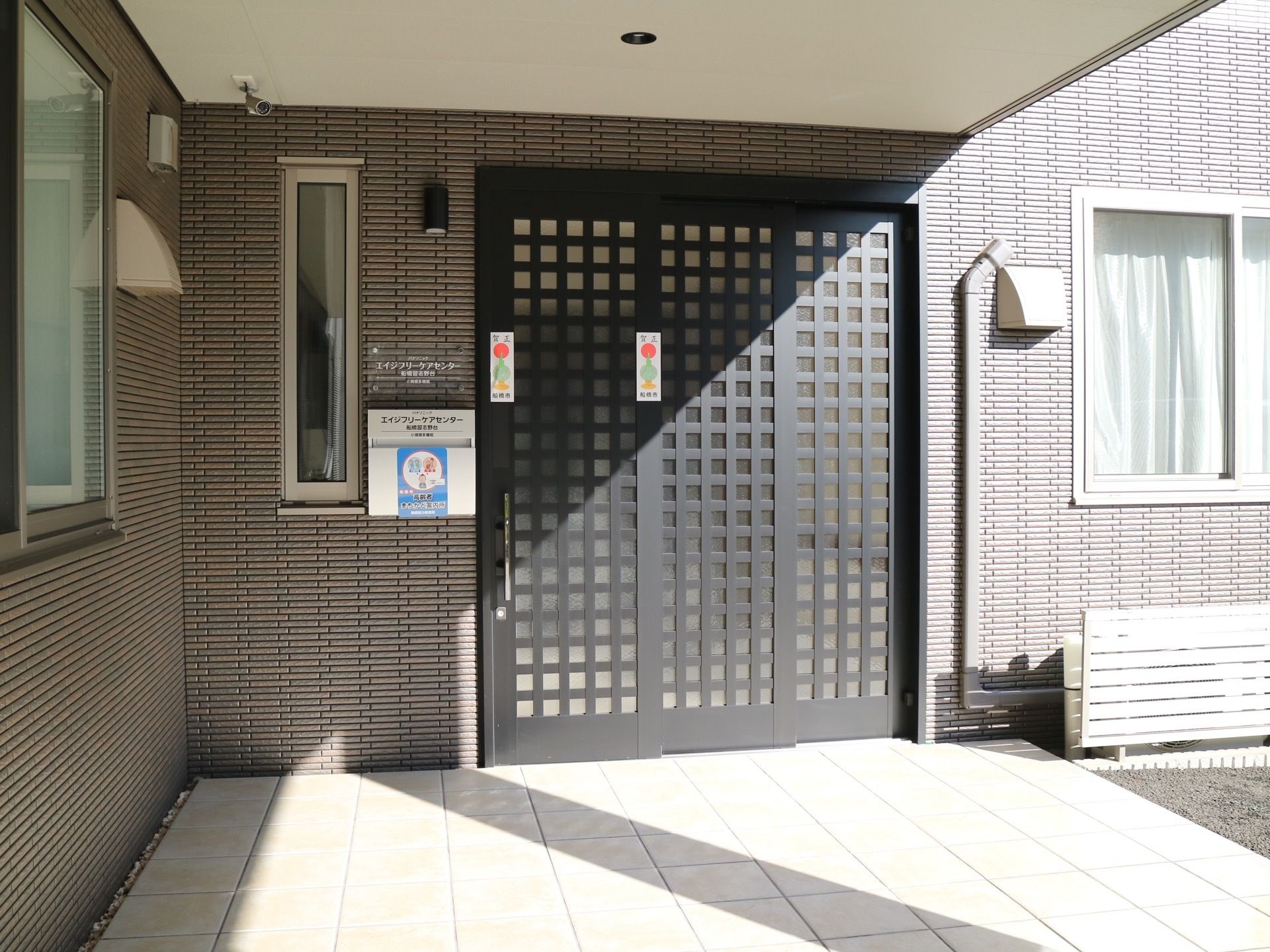 ゆとりある玄関ポーチが設けられている。屋根付きになっており、黒い格子デザインの3枚スライド式扉で、防犯カメラが設置されている。