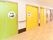 黄色い右側のドアにはトイレのイラストと「お手洗い」と書かれていて、左側のライトグリーンのドアには人が浴槽内に座ったイラストがある。