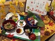 炊き込みご飯やすいものなどが紅葉した紅葉で彩られたテーブルに並べられている。