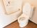 トイレに、蓋つきの便座が設置されている。壁には、呼び出しボタンや便座洗浄機能の操作パネルがまとめて取り付けられている。