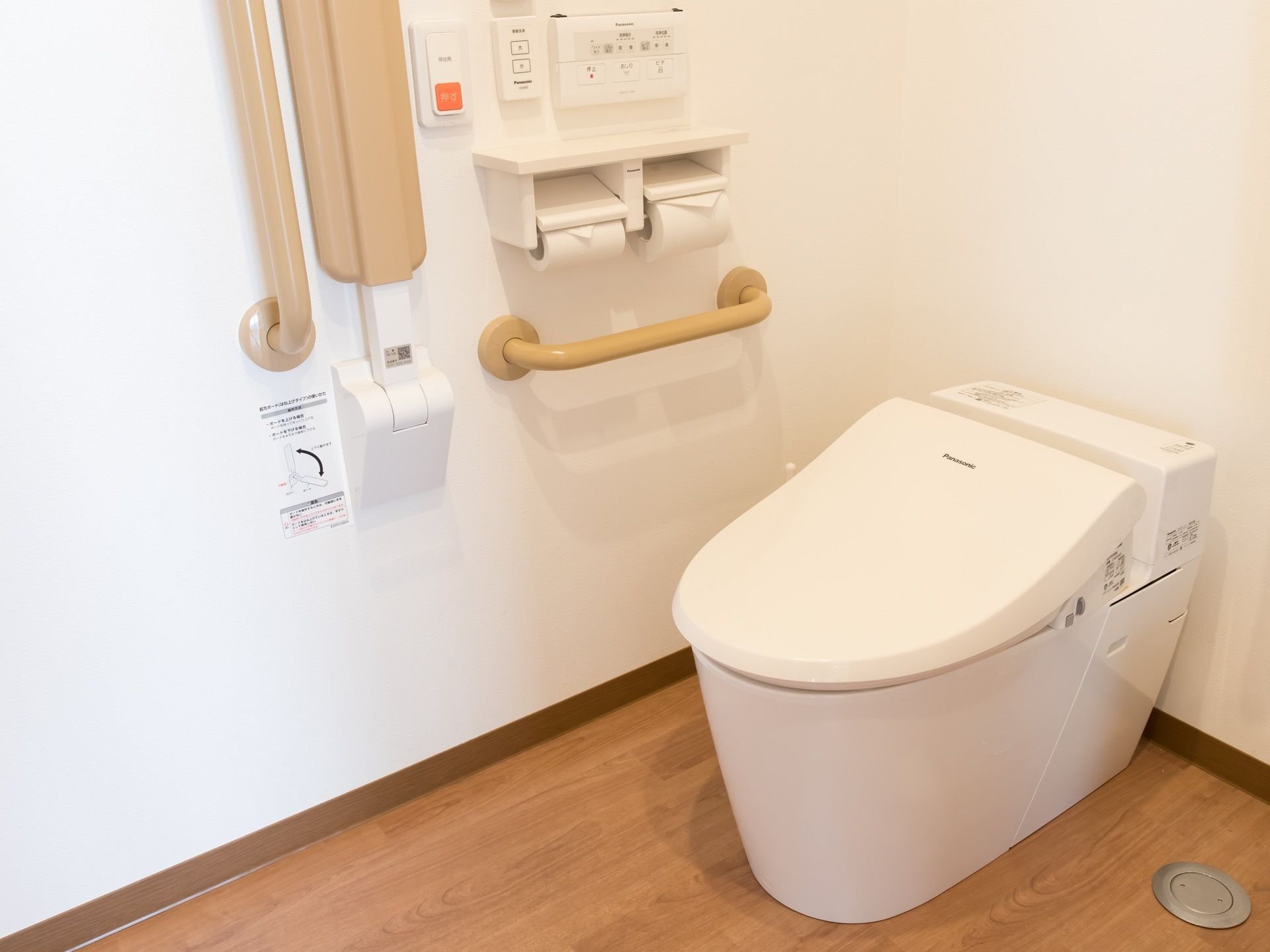 清潔感のあるトイレである。トイレットペーパーが2つ取り付けられていて、その近くには非常用ボタンも設置されている。