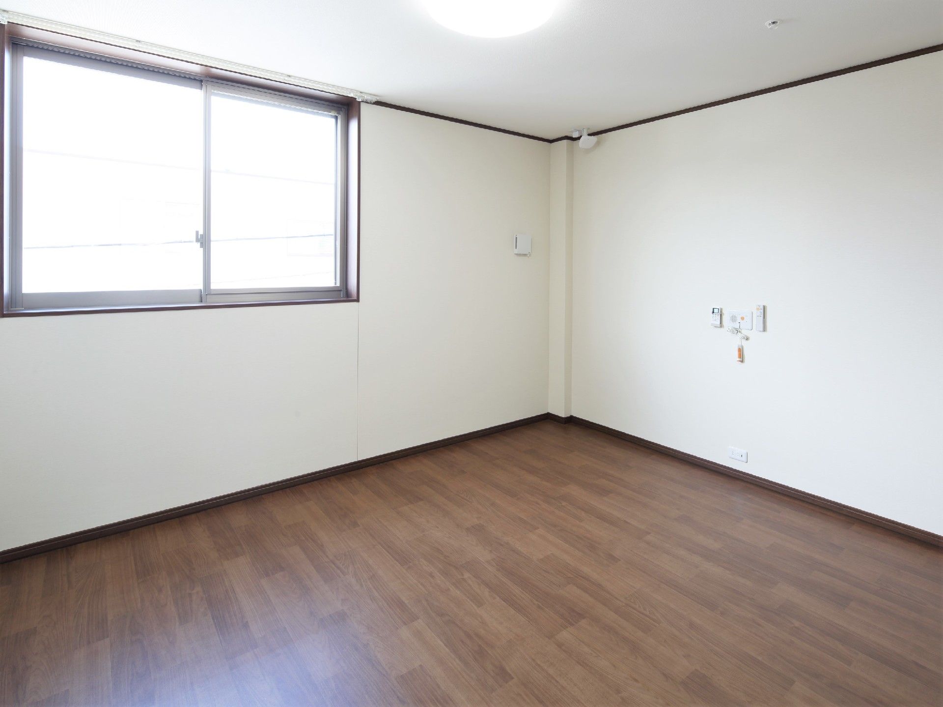 大きな窓が付いたシンプルな居室。緊急通報装置とセンサーが付いている。