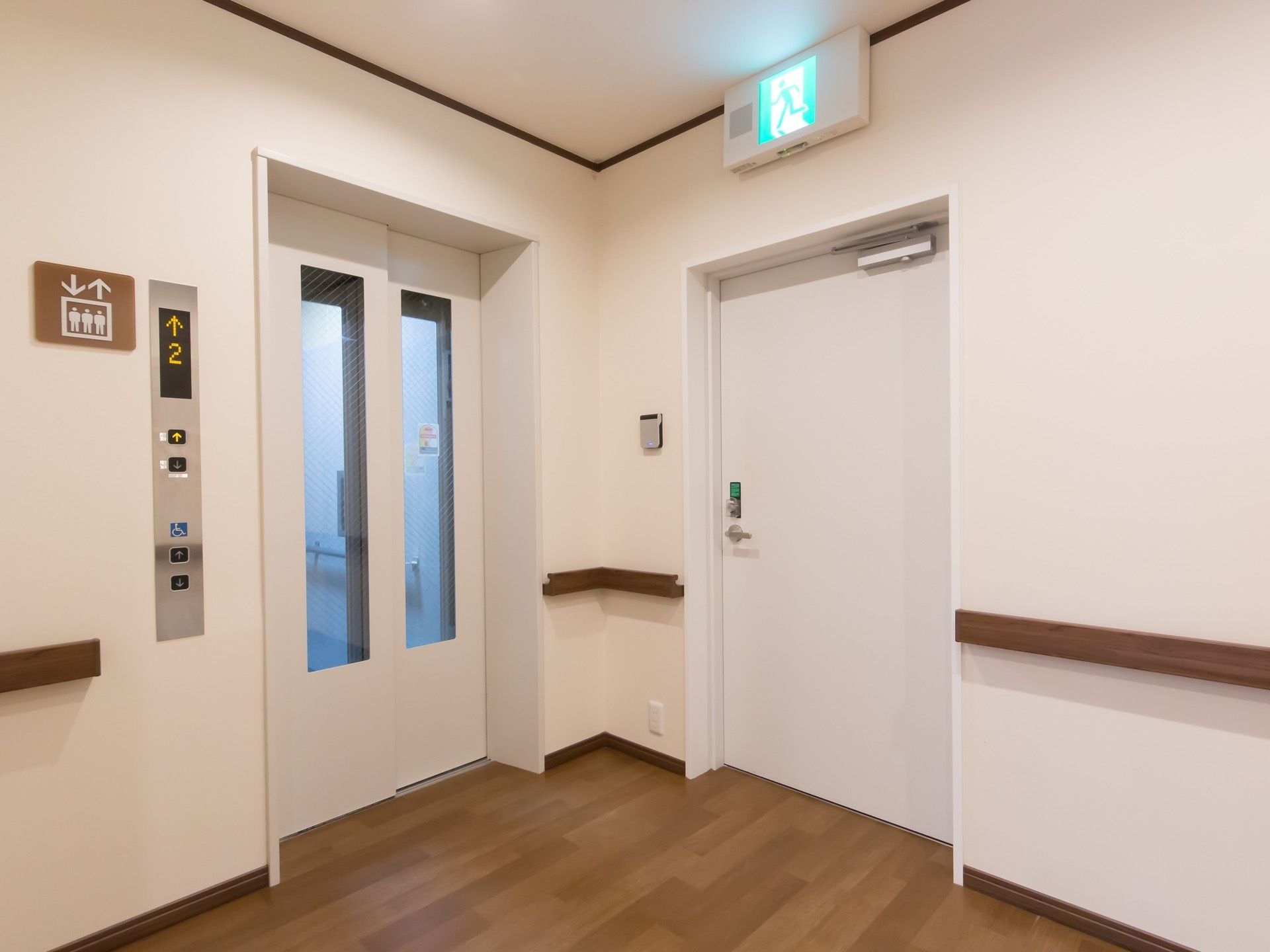 エレベーターが１基設置されており、白を基調とした扉にはガラス窓が付いている。横には、非常階段が設けられている。