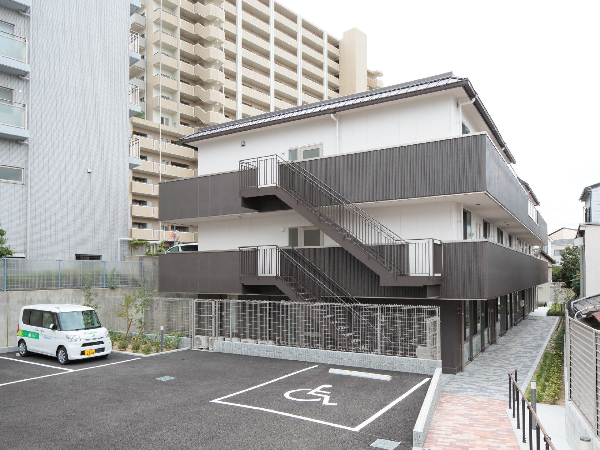 各フロアにベランダがついた3階建ての建物には屋外階段もあり、駐車スペースも用意されている。