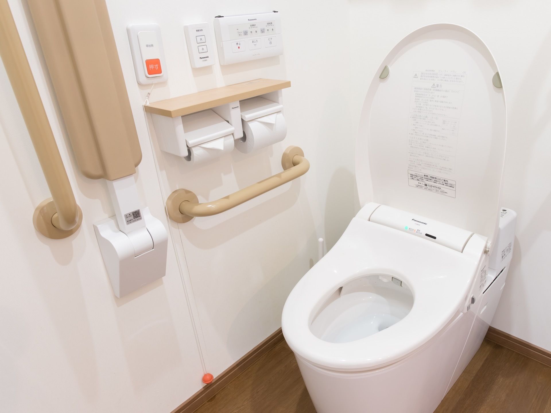 トイレは白い内装で統一され、明るく清潔感がある。便座のそばには手すりや安全バー、呼び出しボタンが完備されている。