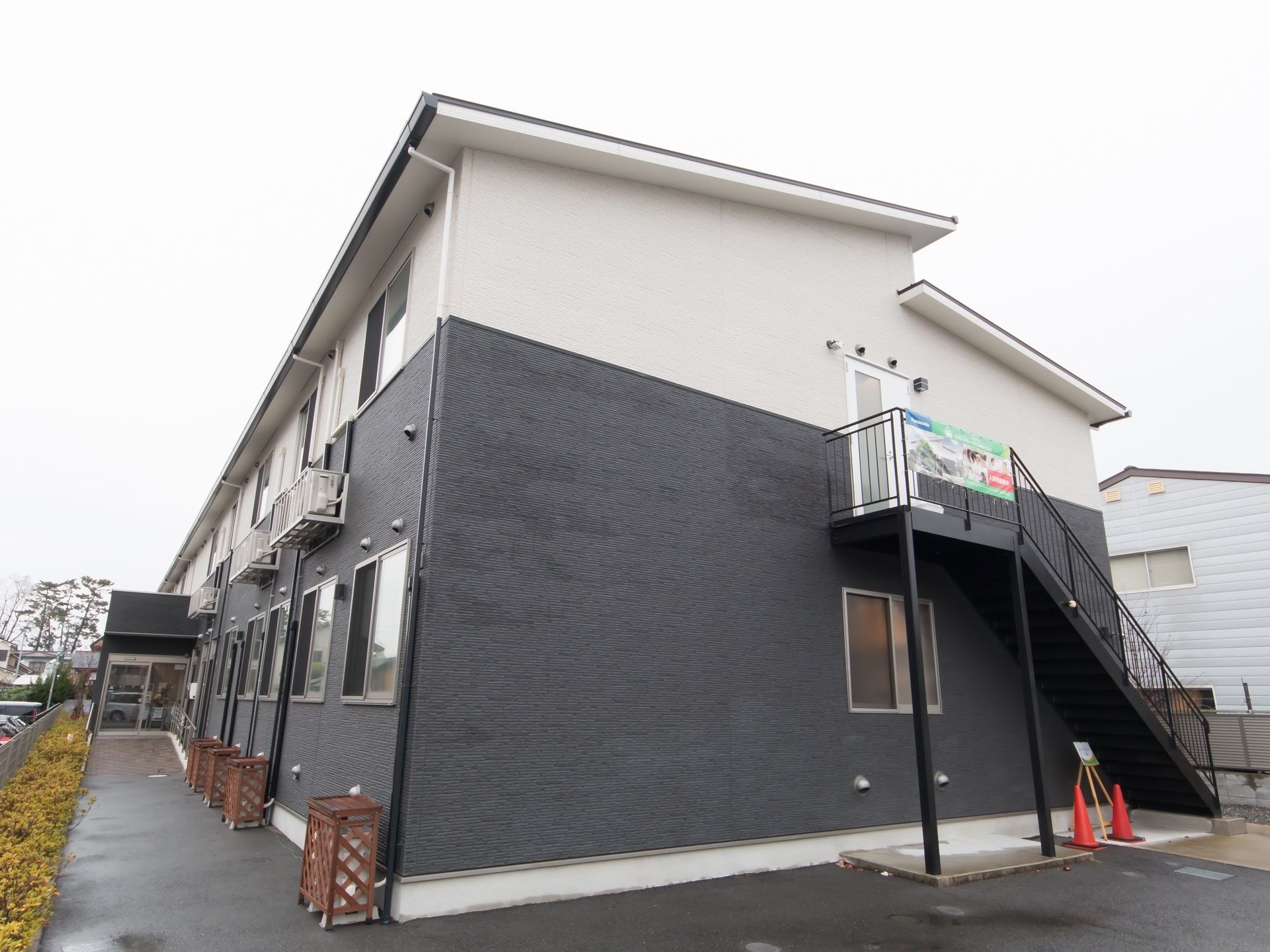 白と黒のツートーンになっているおしゃれな外観である。建物は2階建てで、外には非常用の階段が設置されている。