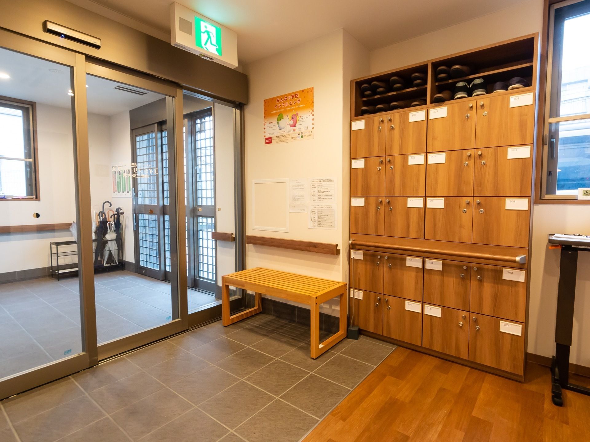 自動ドアが備え付けられた玄関である。腰掛けられる、木製の椅子がある。。壁側には手すりが設置されてある。