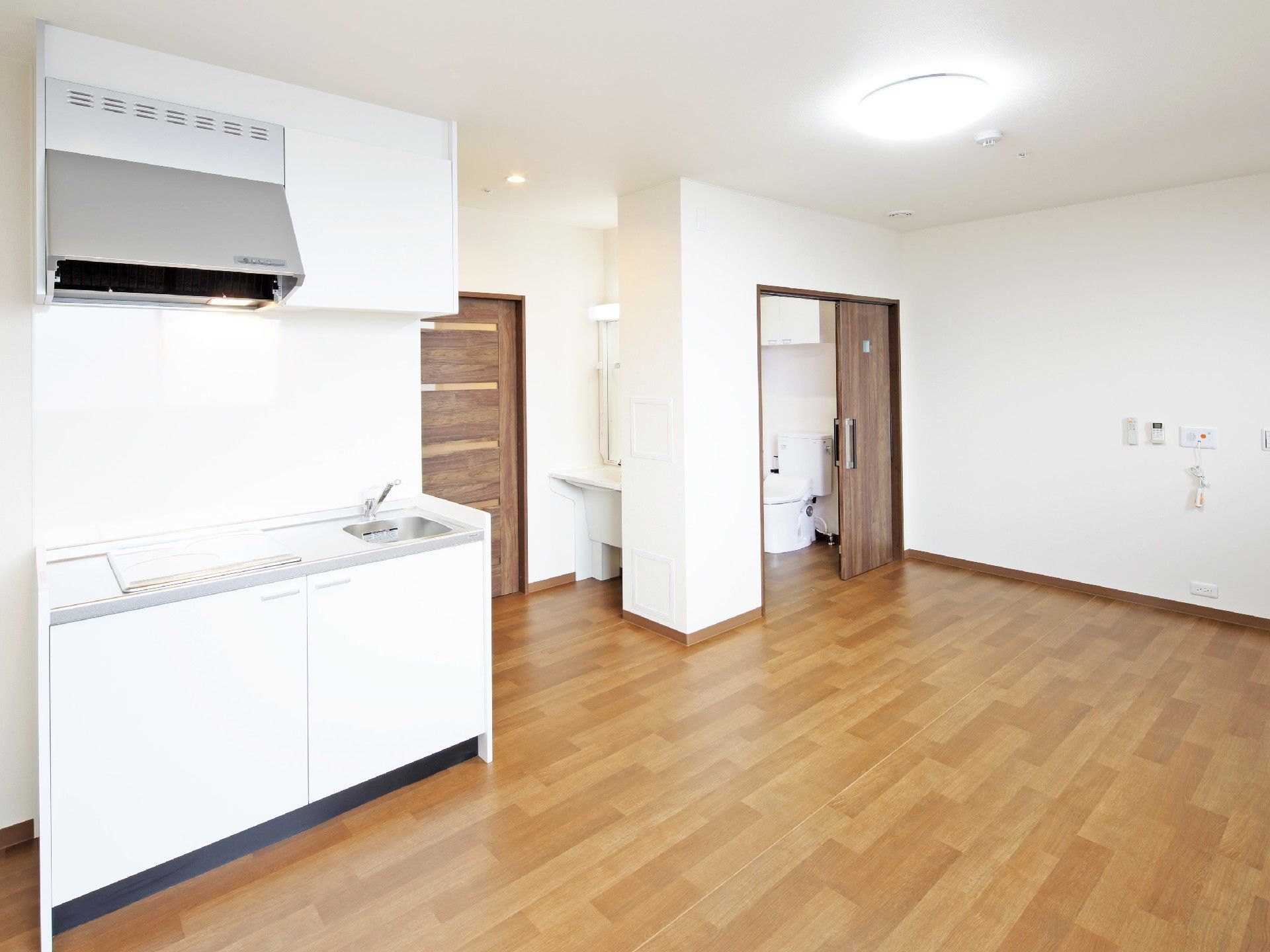 IHクッキングヒーターを設置したキッチンがついた居室にはトイレや洗面所があり、家具は置かれていない。