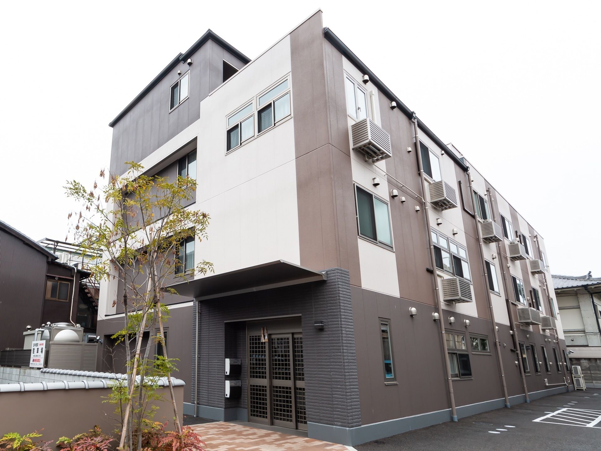 シックなデザインの外観である。エントランスには屋根が設けられている。地面はアスファルトが敷かれてある。