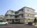 3階建ての建物にはベランダが付き、玄関の周りには木や花も植えられ、駐車スペースもある。