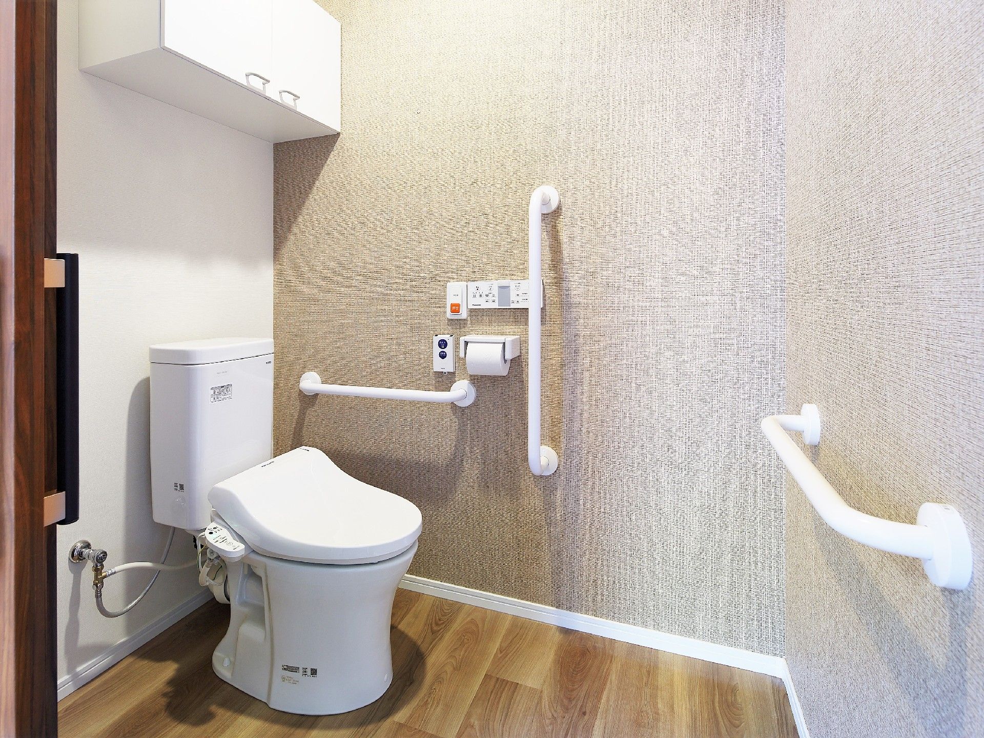 複数の手すりが設置されたトイレは広く、大きな棚も付いている。