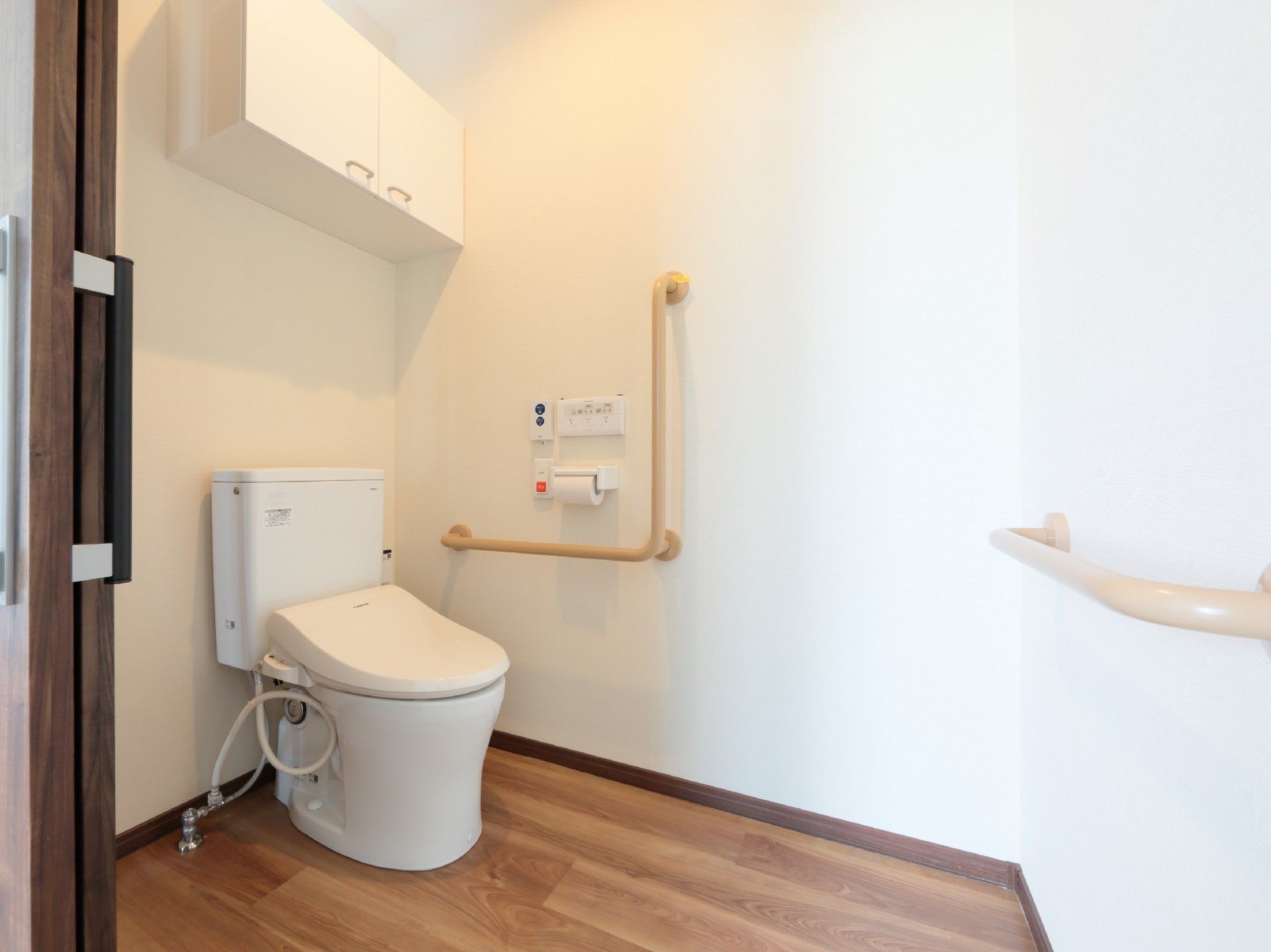 収納や手すり、呼び出しボタンが付いたトイレは広く、フローリング。