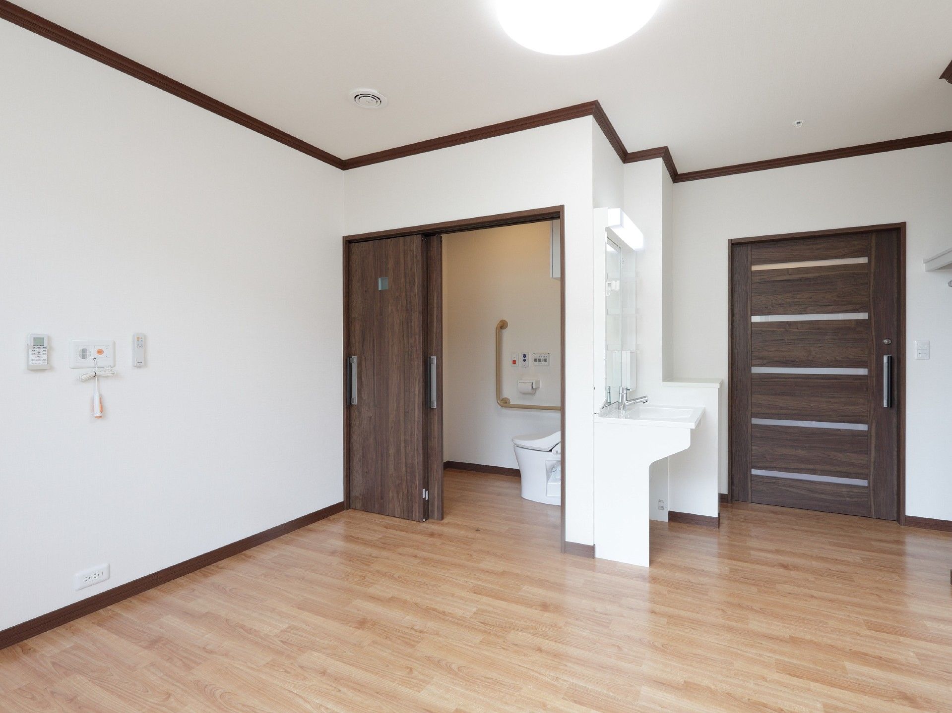 シンプルなフローリングの居室。家具などはなく、トイレと洗面、照明と出入り口の引き戸があるのみ。