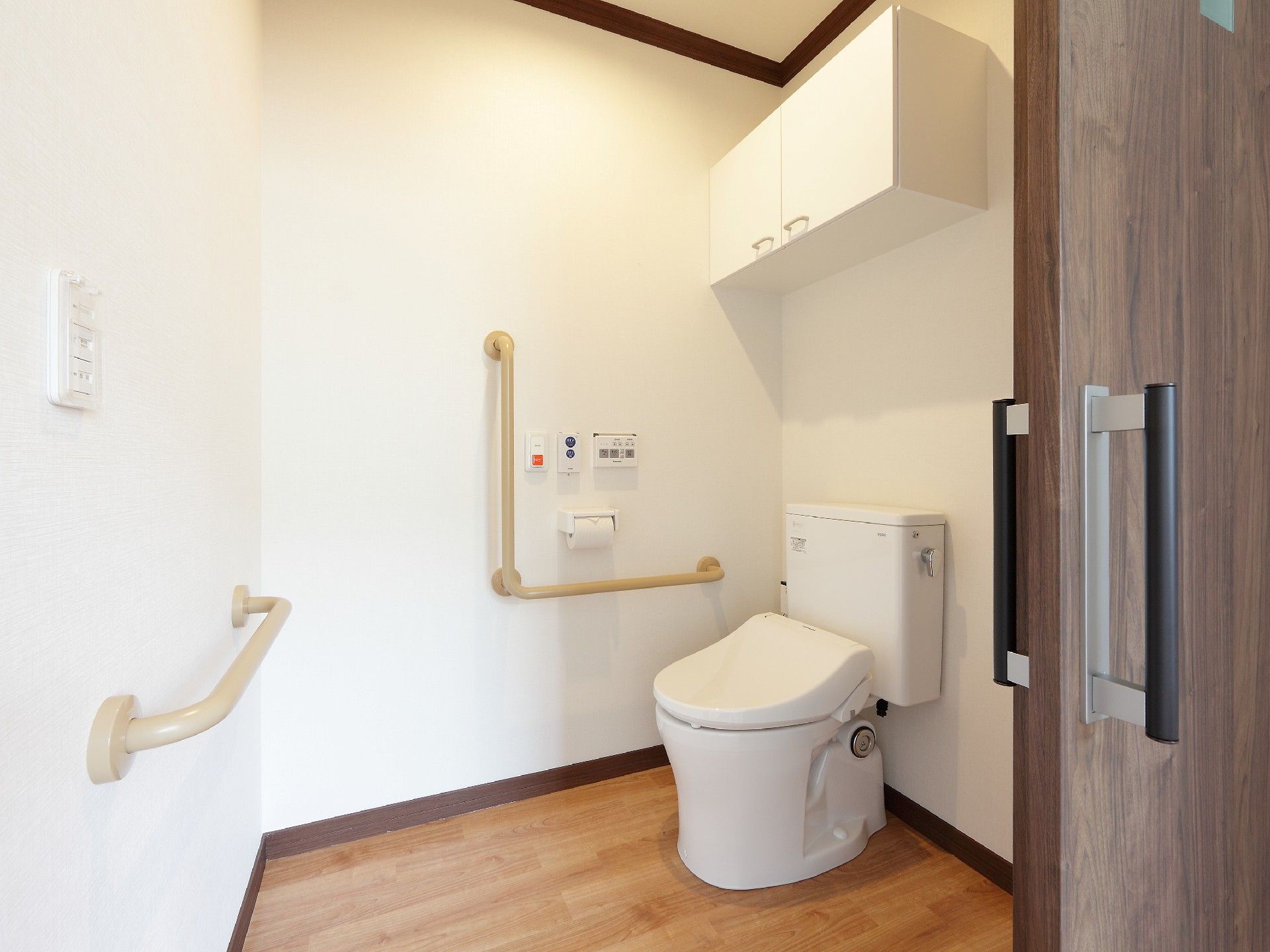 シンプルなトイレには手すりが付き、車いす対応の広さを確保。オレンジの呼び出しボタンも付いている。