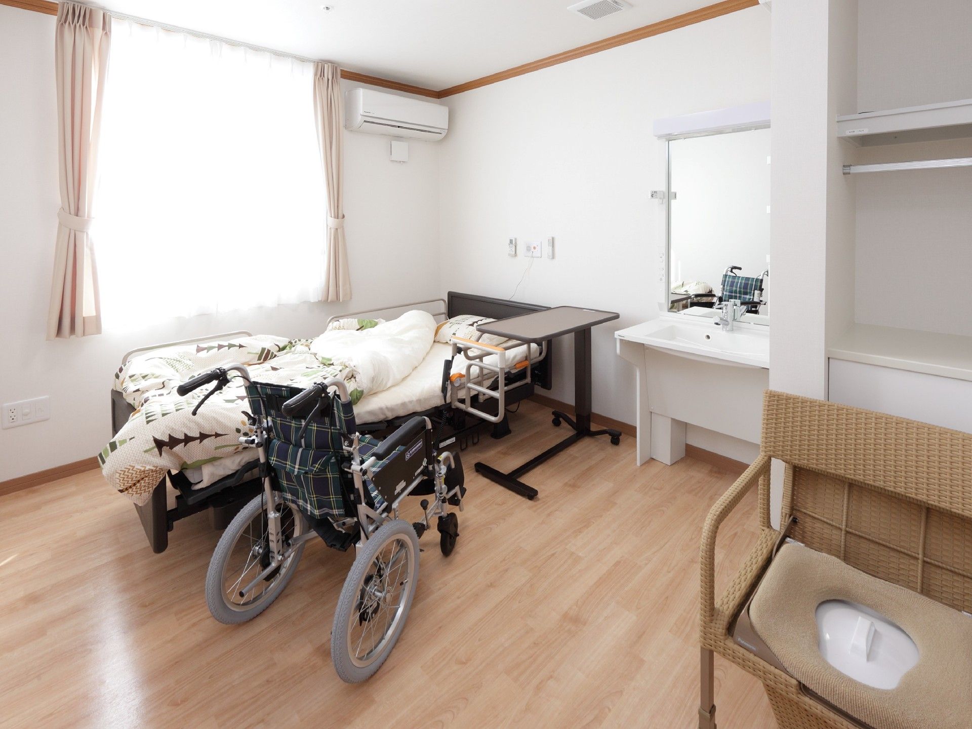 寝具付きのベッドが中央に置かれたフローリングの居室には、洗面所やポータブルトイレも付いている。
