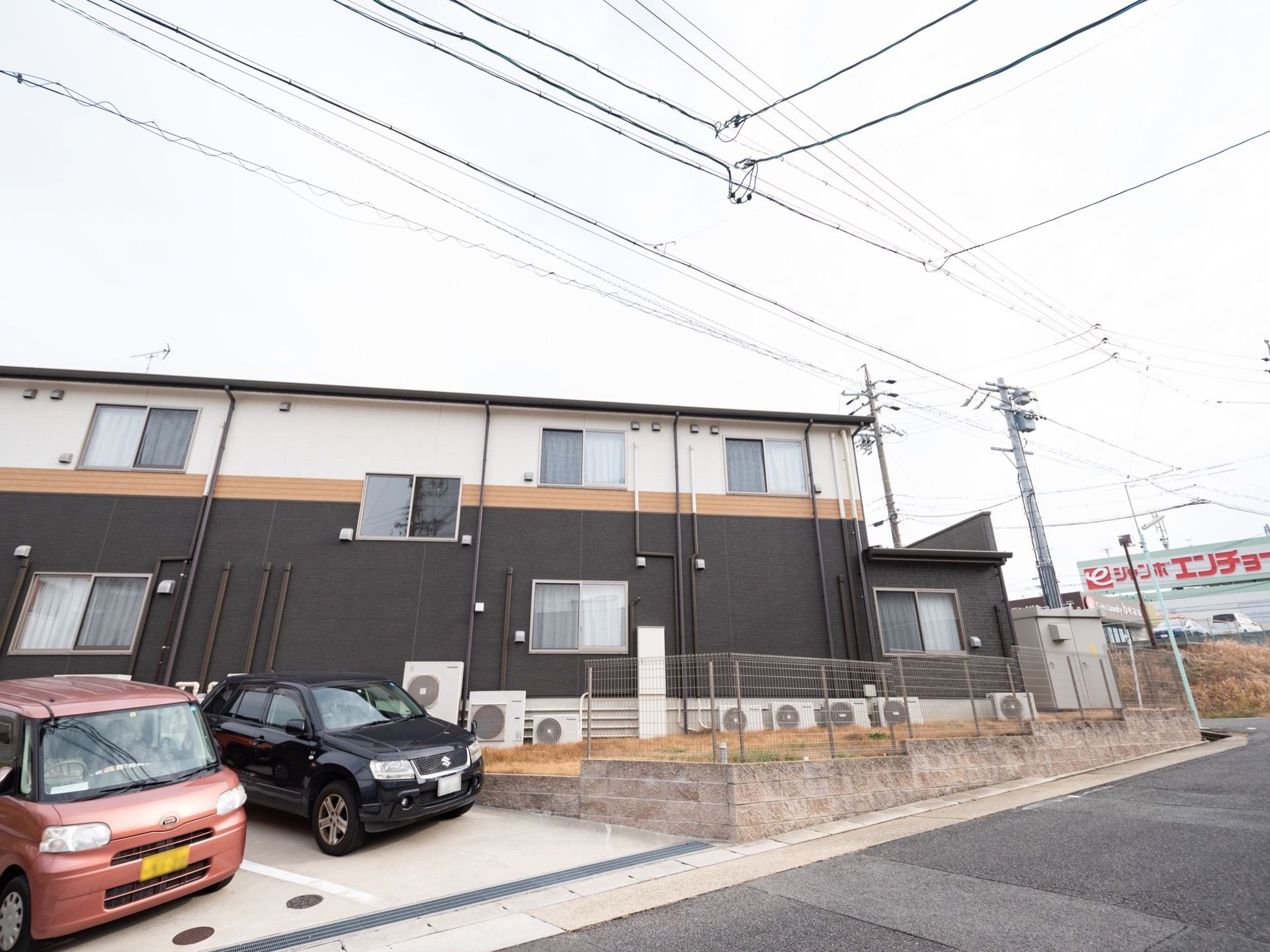 施設は2階建てで、1階外壁は黒系、2階外壁は白である。公道より少し高い位置にあり、建物脇に駐車場が設けてある。