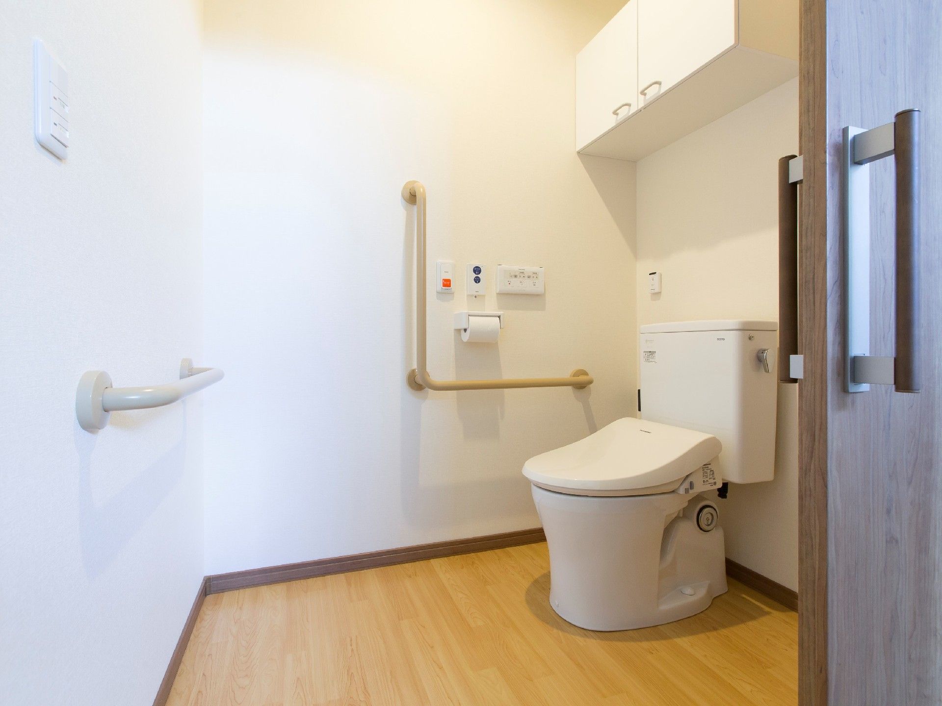 手すりや呼び出しボタンが付いたトイレはシンプルな造り。介助スペースが広い。