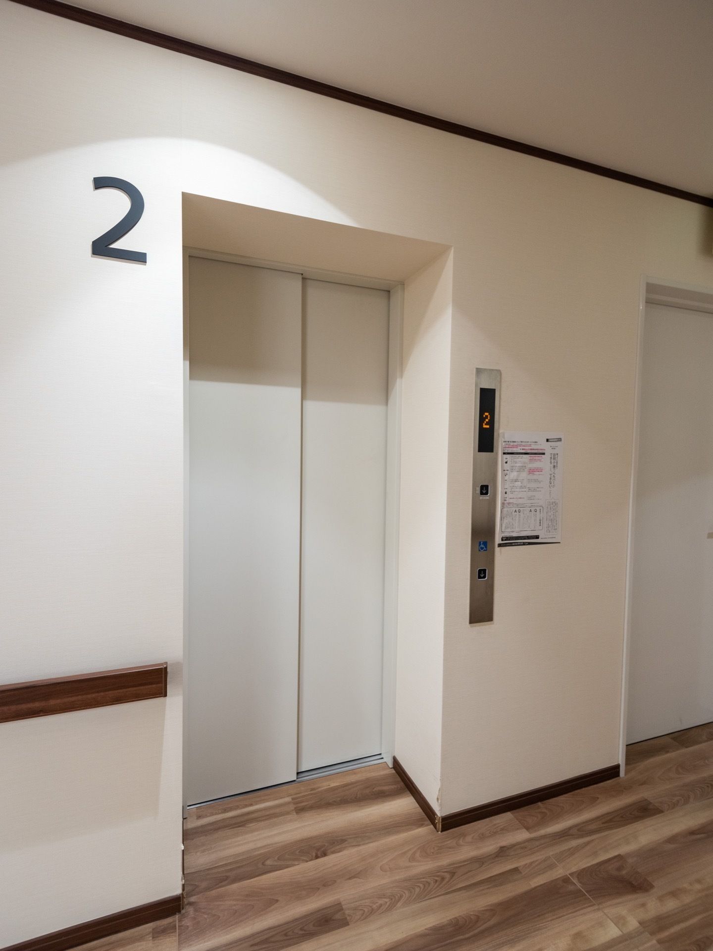 白い扉のエレベーターが1基設置されている。壁には階数を表す数字が取付けられており、床はフローリングになっている。