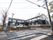 2階建てで白と濃い灰色のツートンカラーの建物。建物前に駐車場が設けられている。