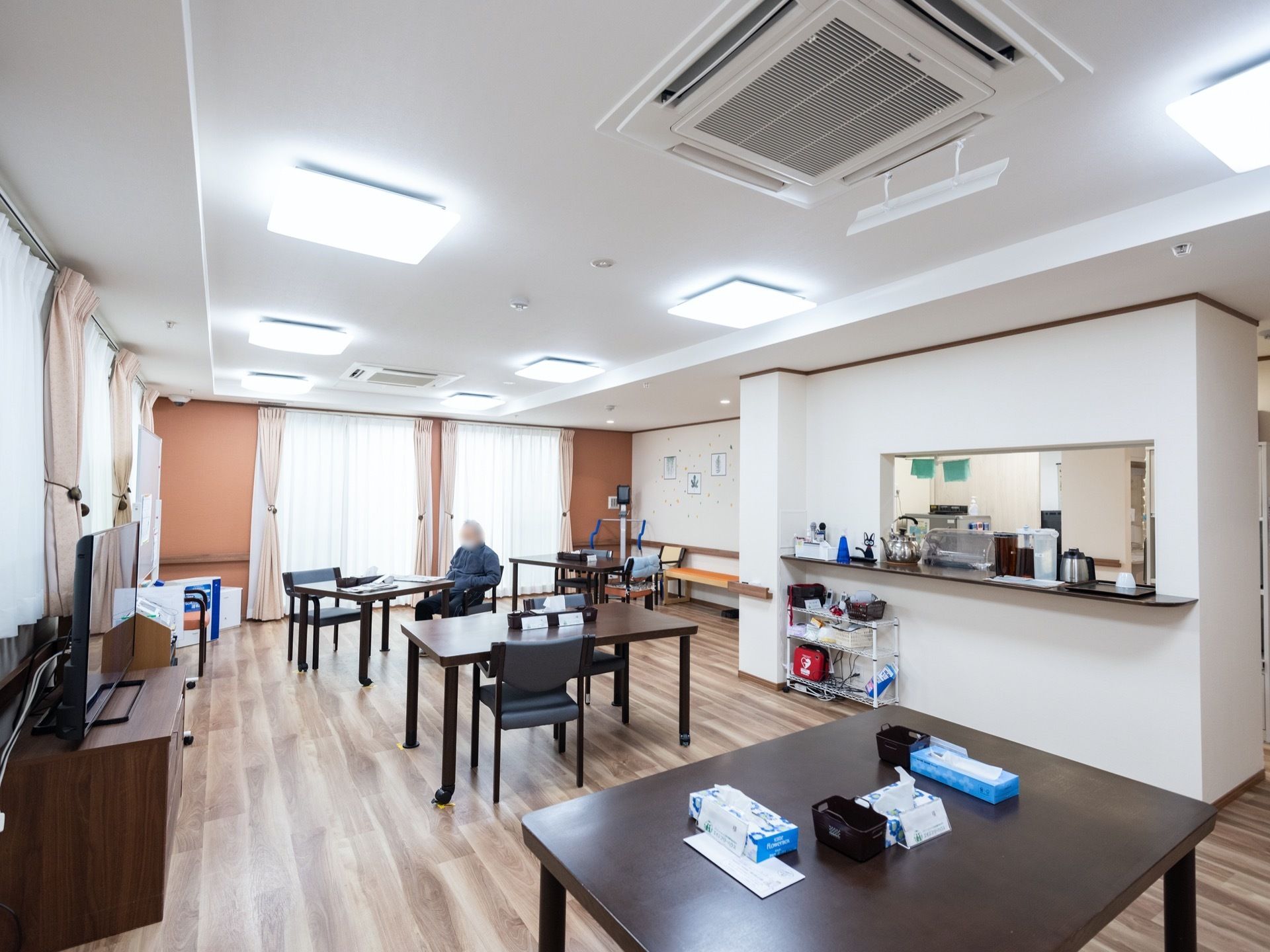 部屋全体に、複数のテーブルと椅子が置かれており、天井には、シーリングライトが規則的に並べて設置されている。