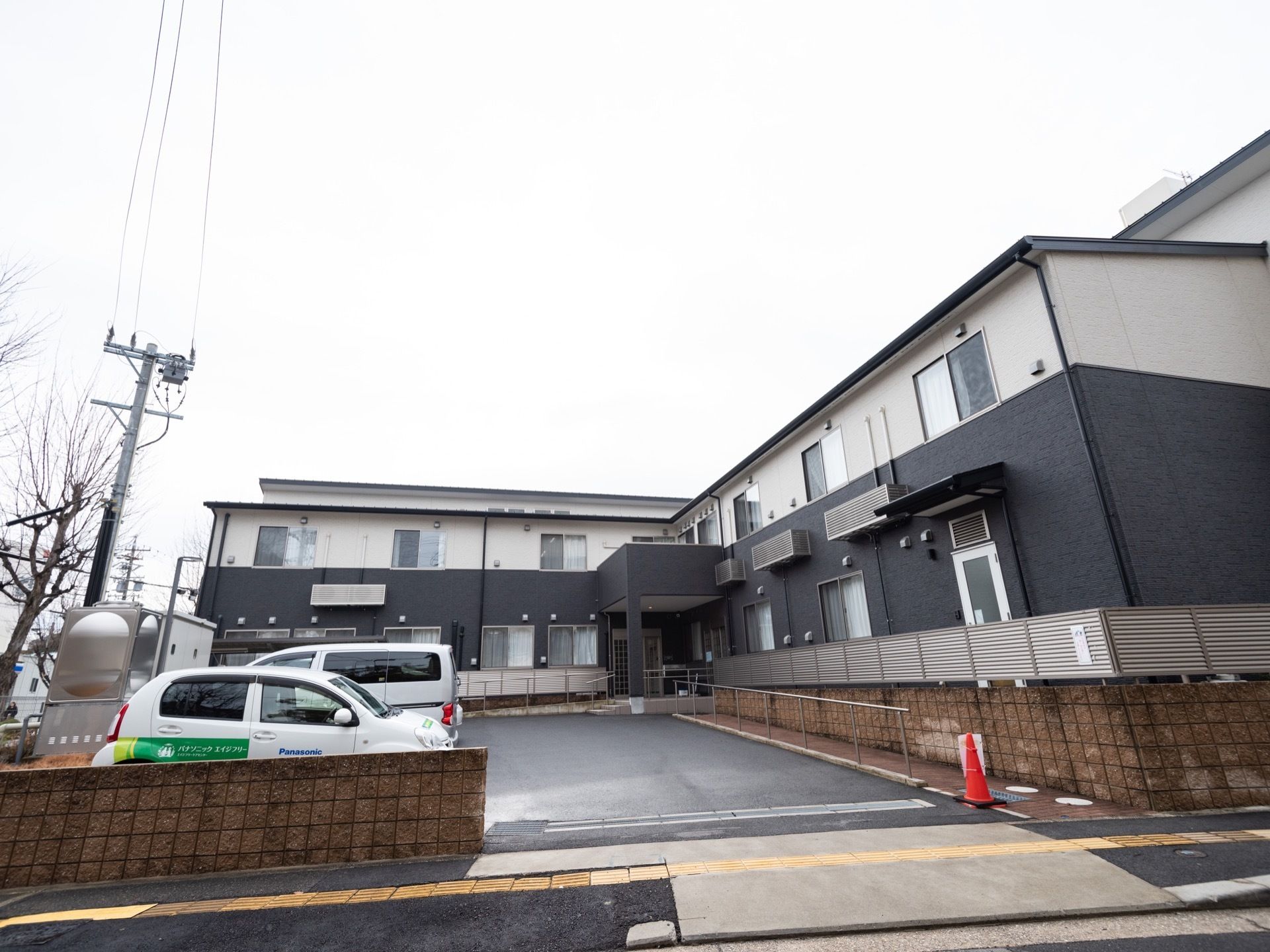 ツートンカラーで構成された外壁の２階建ての建物である。施設の周囲をブロック塀で囲んでおり、付近には電柱がある。