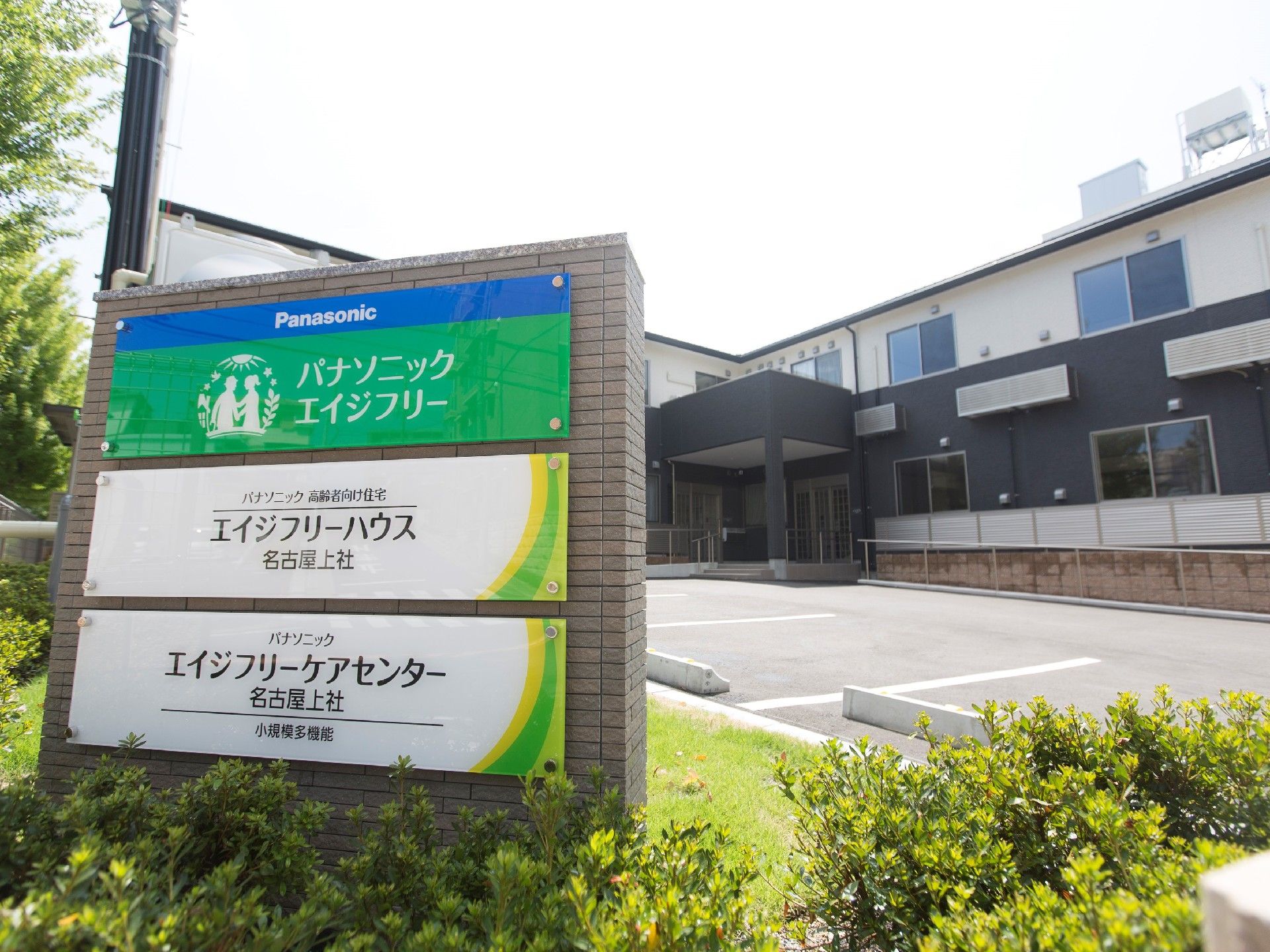 2階建ての建物。1階部分はダークグレー、2階部分は白で、玄関にはスロープと屋根もある。