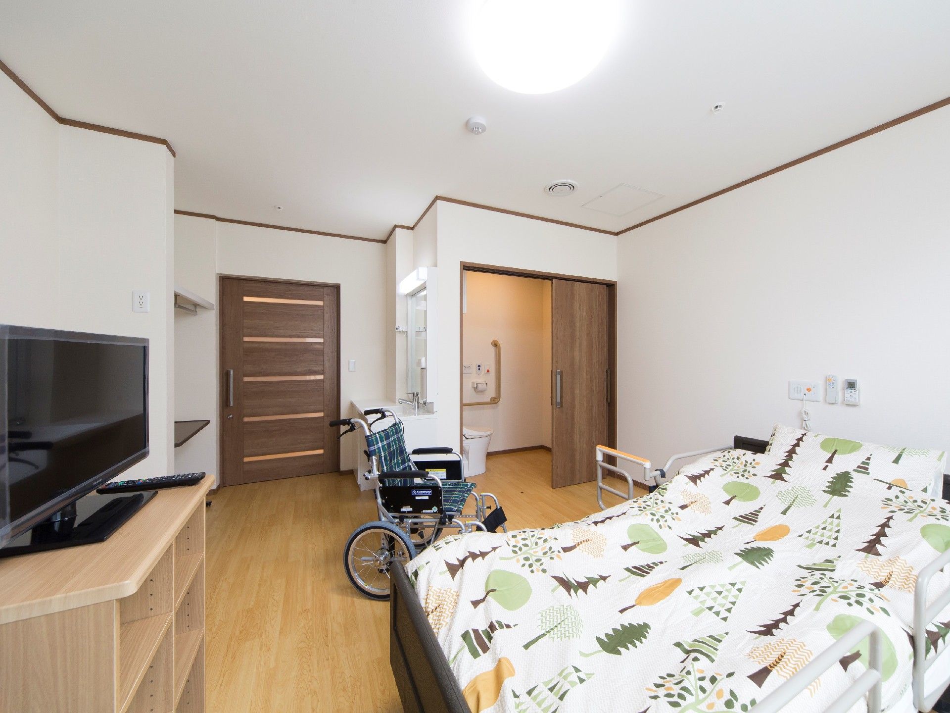 ベッドやテレビが設置された居室はシンプルで、車いす対応のトイレや洗面所が付いている。