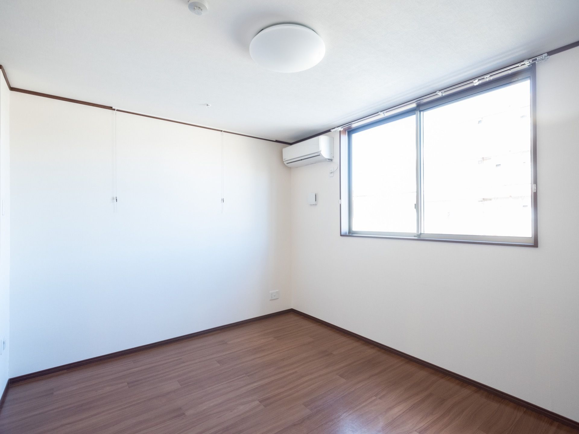 居室は白色の天井、壁に木目調のフローリングというデザインである。大きな窓からは外光が差し込み、空調も完備されている。