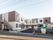 屋外階段やベランダが付いた建物は2階建てでシンプルなデザイン。広い駐車スペースや看板もある。