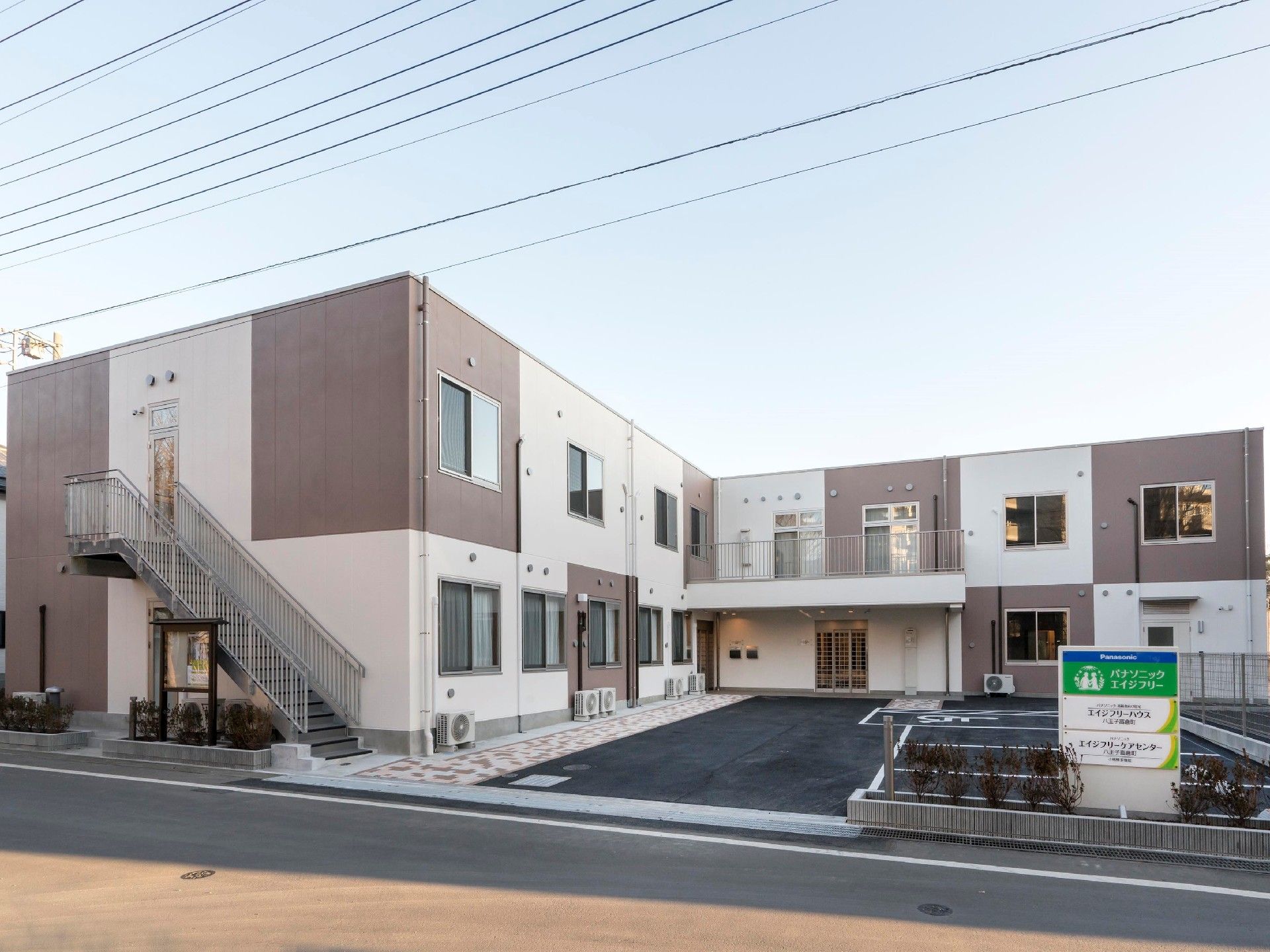 2階建ての建物。ブラウンとベージュのモザイク模様で、側面には屋外階段もある。
