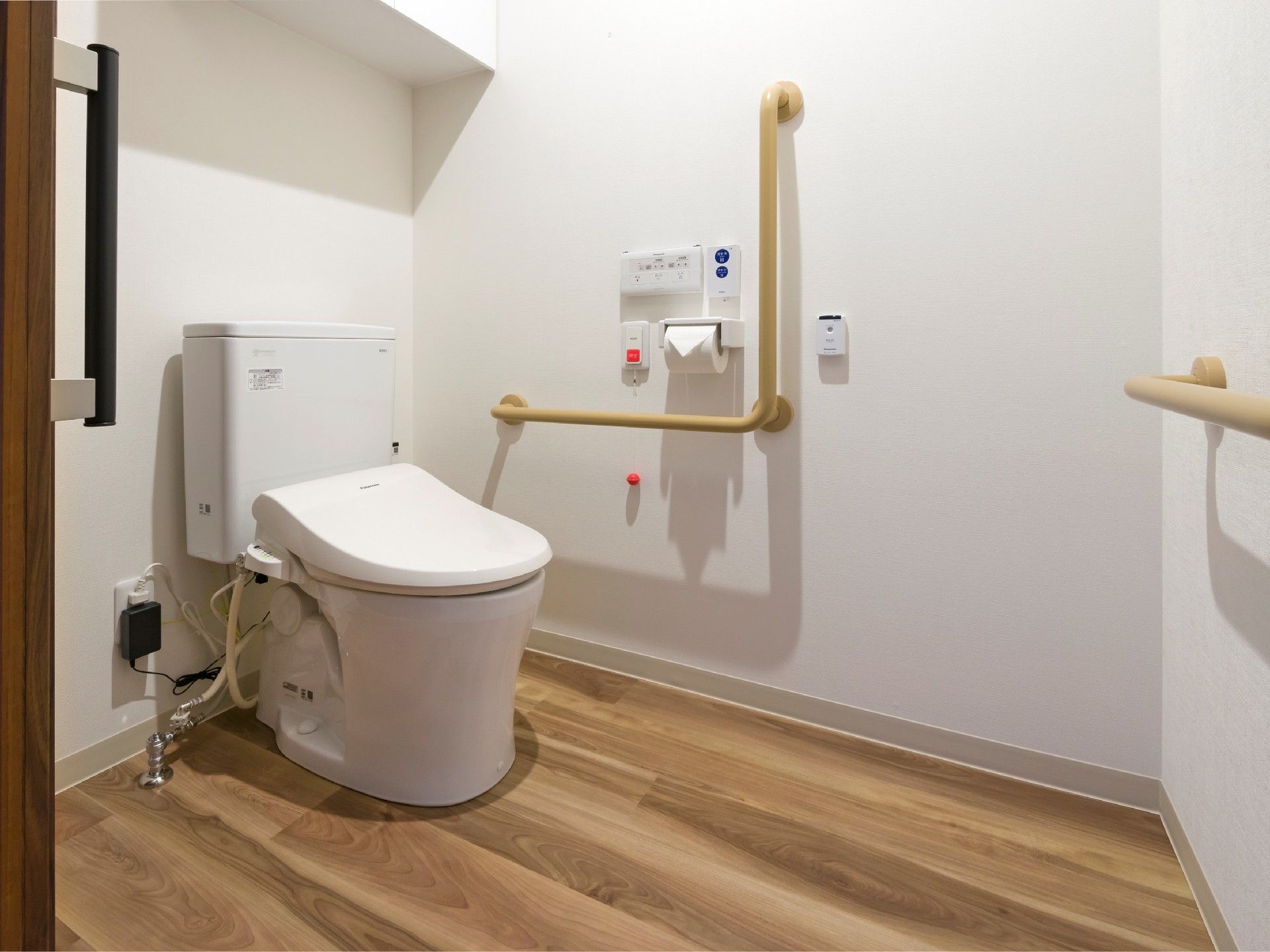 呼び出しボタンがついたトイレにはエル字型の手すりがあり、フローリングで介助スペースも広い。