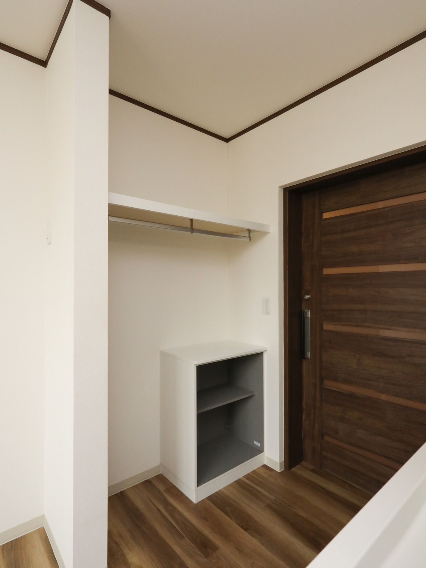 木目調の引き戸で仕切られた居室がある。入るとすぐに下駄箱や衣類掛けの付いた収納スペースが設けられている。