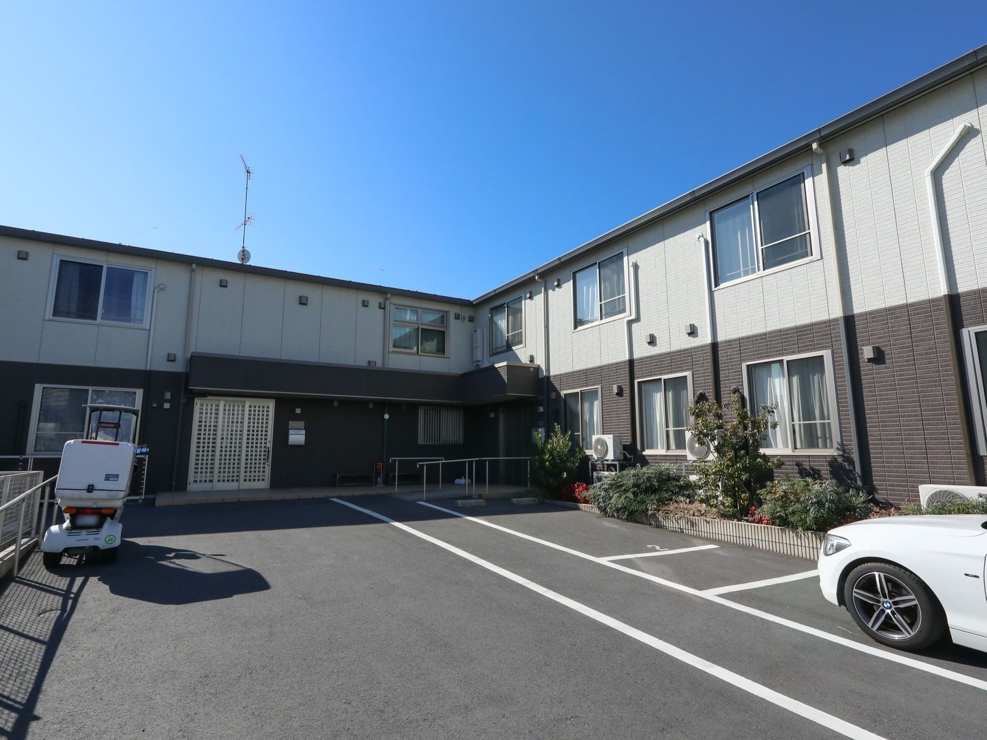 建物はL字型になっていて、車が通れるように広く通路が設置されている。白とグレーのツートンカラーが印象的な外観。