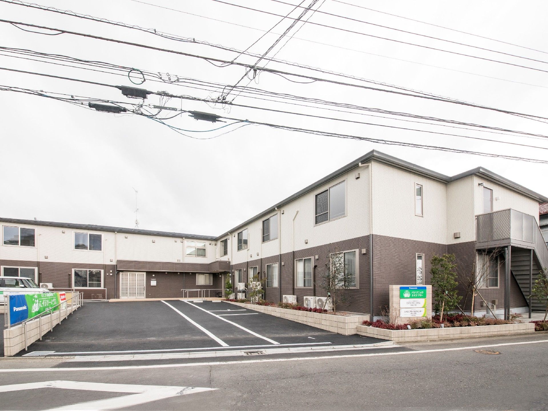 2階建ての建物は横に長く、屋外階段もあり、とても広い駐車場が付いている。
